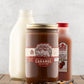 Jar of Fat Toad Farm Mulled Cider caramel in front of a bottle of apple cider and a bottle of milk on a wood table
