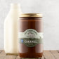 32oz jar of Fat Toad Farm Original Caramel Sauce in front of a bottle of milk on a wood surface