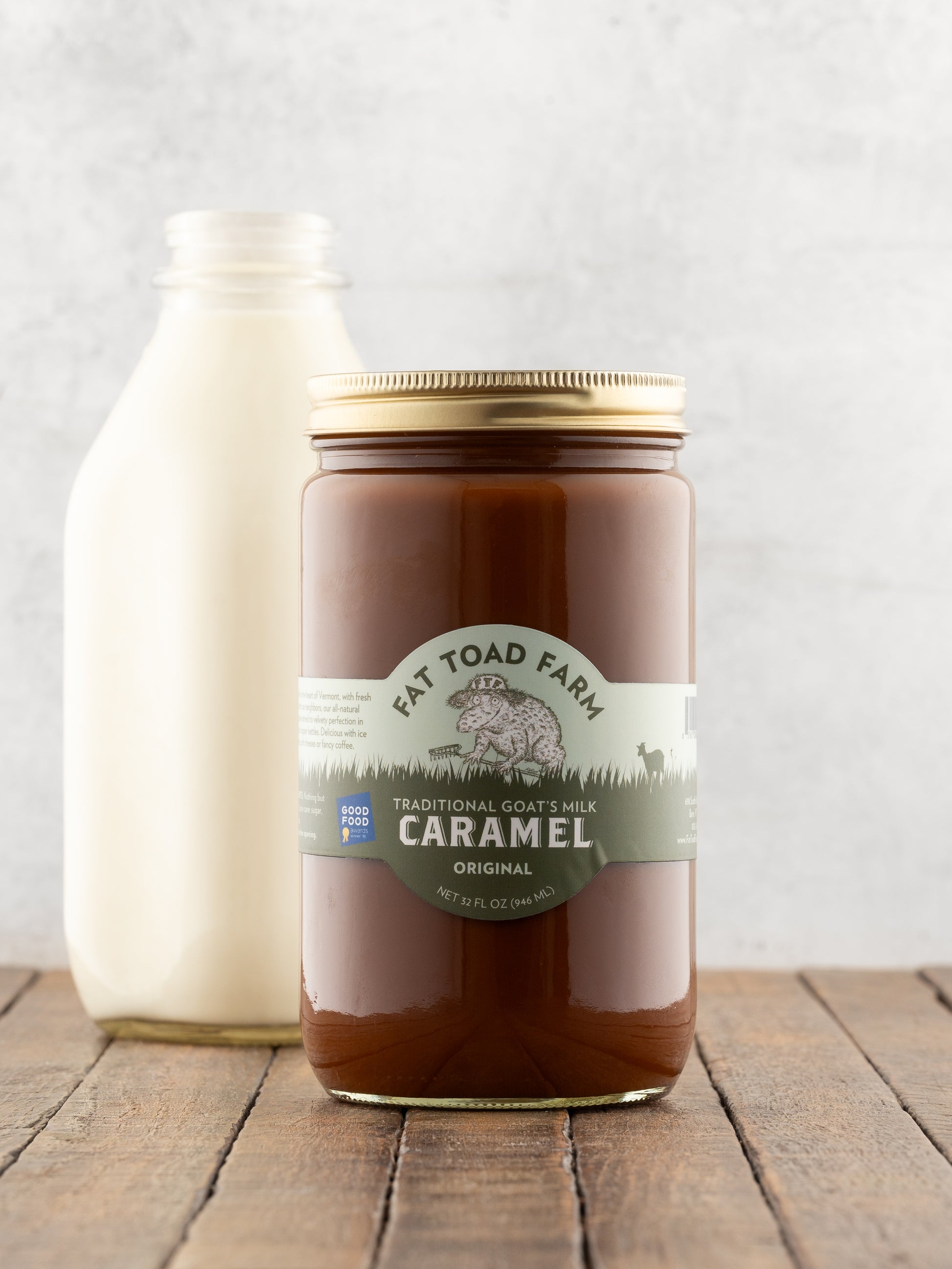 32oz jar of Fat Toad Farm Original Caramel Sauce in front of a bottle of milk on a wood surface