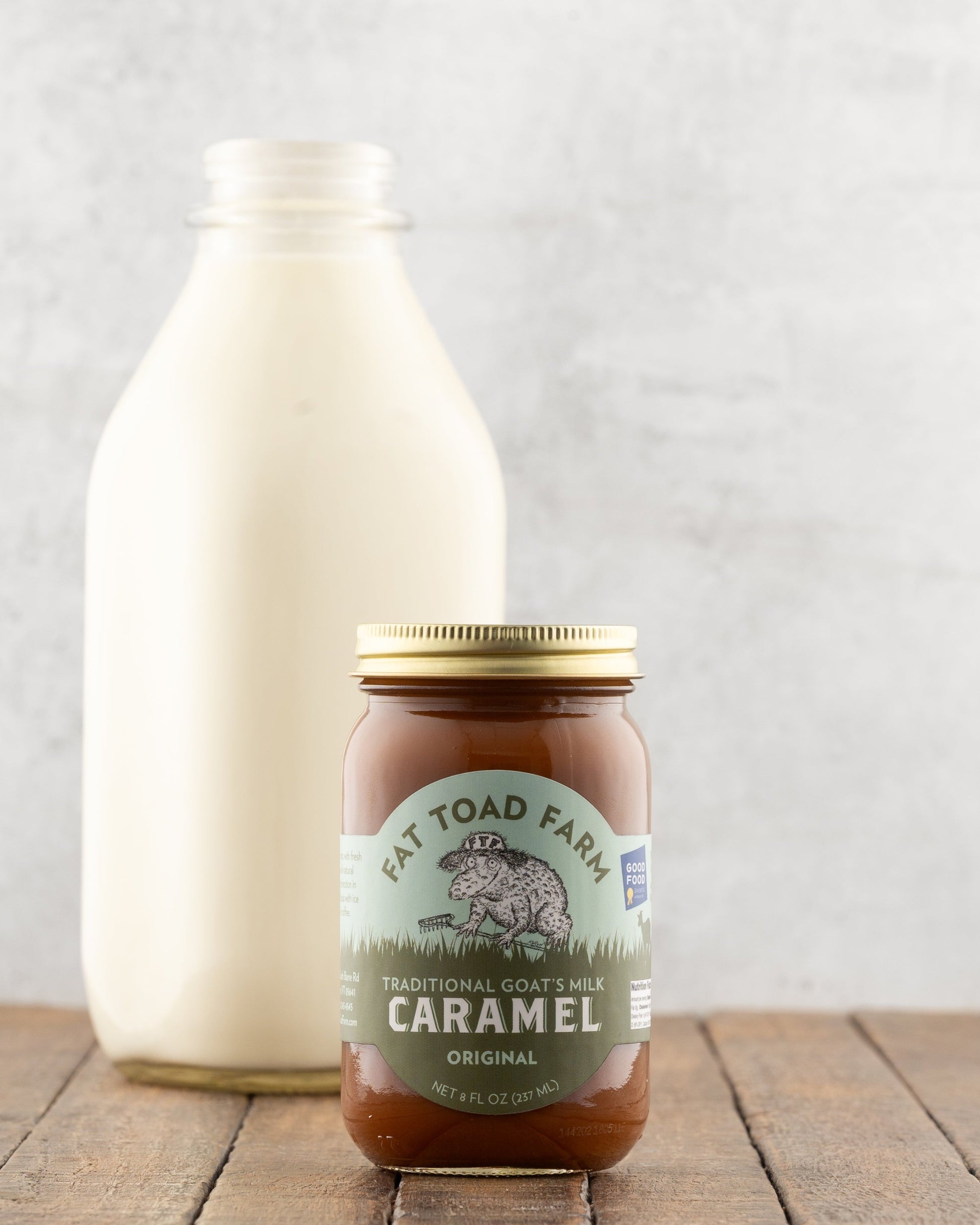 Fat Toad Farm Original Caramel Sauce in front of a bottle of milk on a wood surface