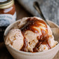 Bowl of ice cream with caramel sauce next to a jar of caramel