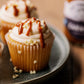 Cupcakes with frosting and caramel sauce on a plate next to a jar of caramel.