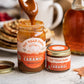 Fat Toad Farm caramel being poured into a jar with a bottle of syrup in the background.