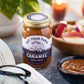 Jar of Fat Toad Farm caramel sauce on a table with apples and a book.