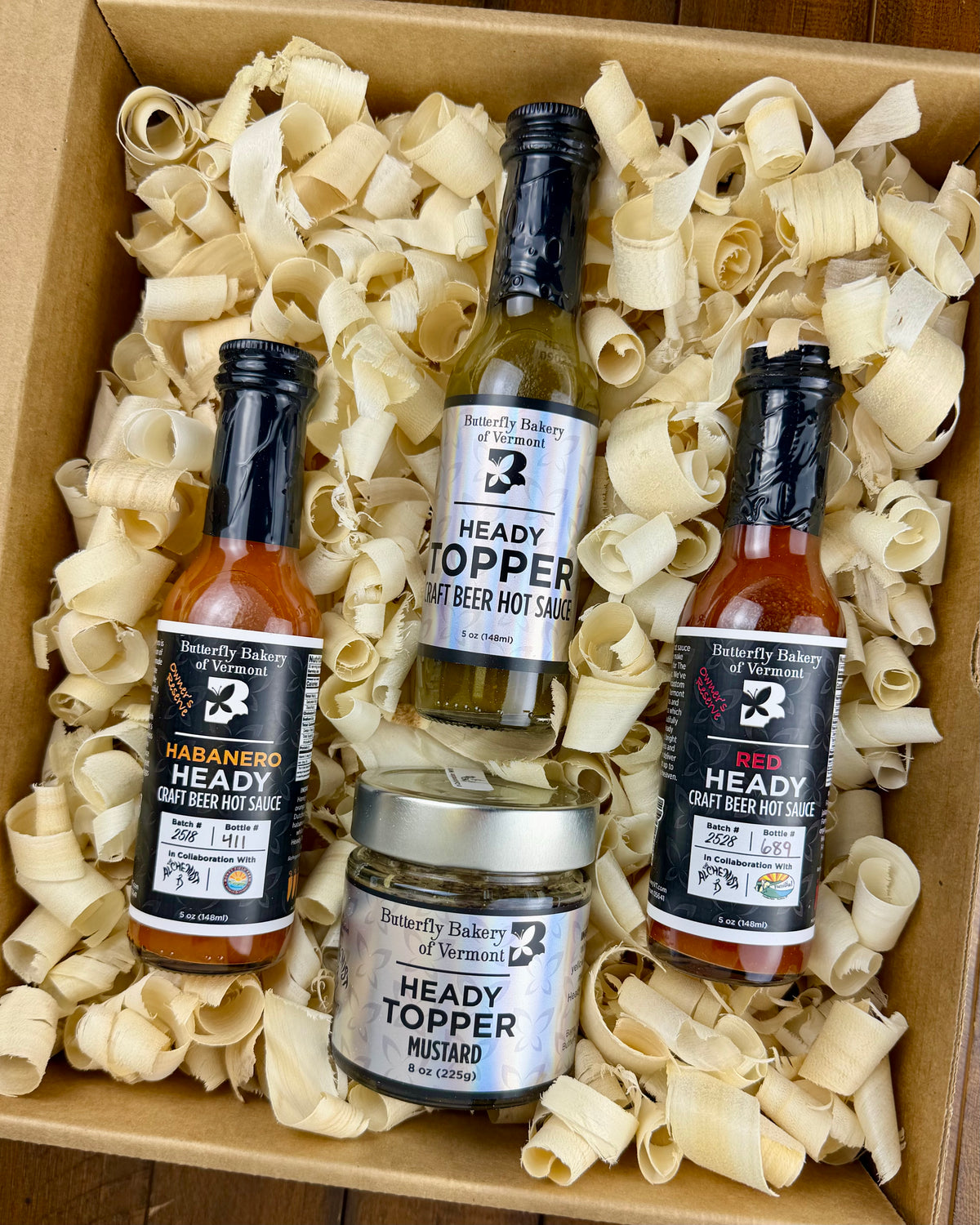 Box of Butterfly Bakery of Vermont Heady Topper hot sauces and mustard with wood shavings