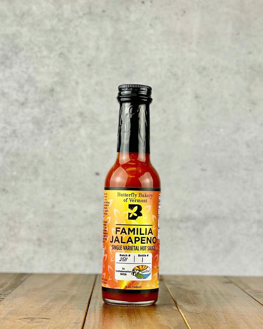 Bottle of Familia Jalapeno single varietal hot sauce from Butterfly Bakery of Vermont on a wood table