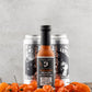 Butterfly Bakery of Vermont Habanero Heady Hot Sauce in front of two cans of Heady Topper beer on a wood surface and orange habanero peppers in the foreground