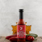 Bottle of Maple Sugar Shack Sriracha Hot Sauce with decorative elements on a wooden surface