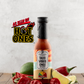 Bottle of Butterfly Bakery of Vermont Taco Vibes Only Hot Sauce aside lime, hot peppers and garlic scapes on a wood surface and the 'As Seen on Hot Ones' logo.
