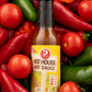 Bottle of Hot House Hot Sauce from Butterfly Bakery of Vermont lying on a bed of hot peppers and tomatoes