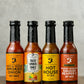 Bottles of all four hot sauces from Butterfly Bakery of Vermont that have appeared on Hot Ones, all on a wooden surface