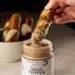 Someone dipping a soft pretzel stick into a jar of Heady Topper mustard from Butterfly Bakery of Vermont