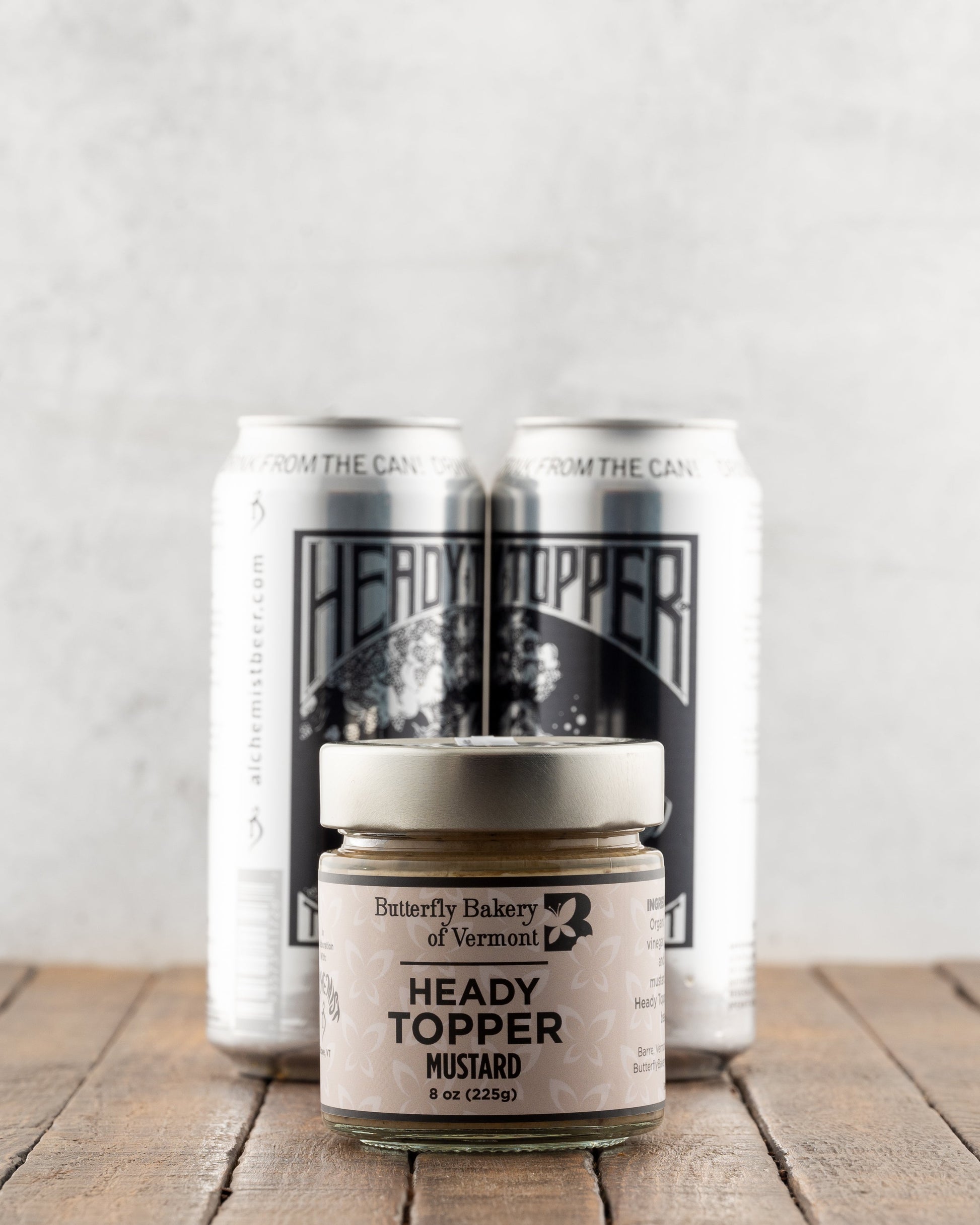 Butterfly Bakery of Vermont Heady Topper Mustard on a wood surface with 2 cans of Heady Topper beer