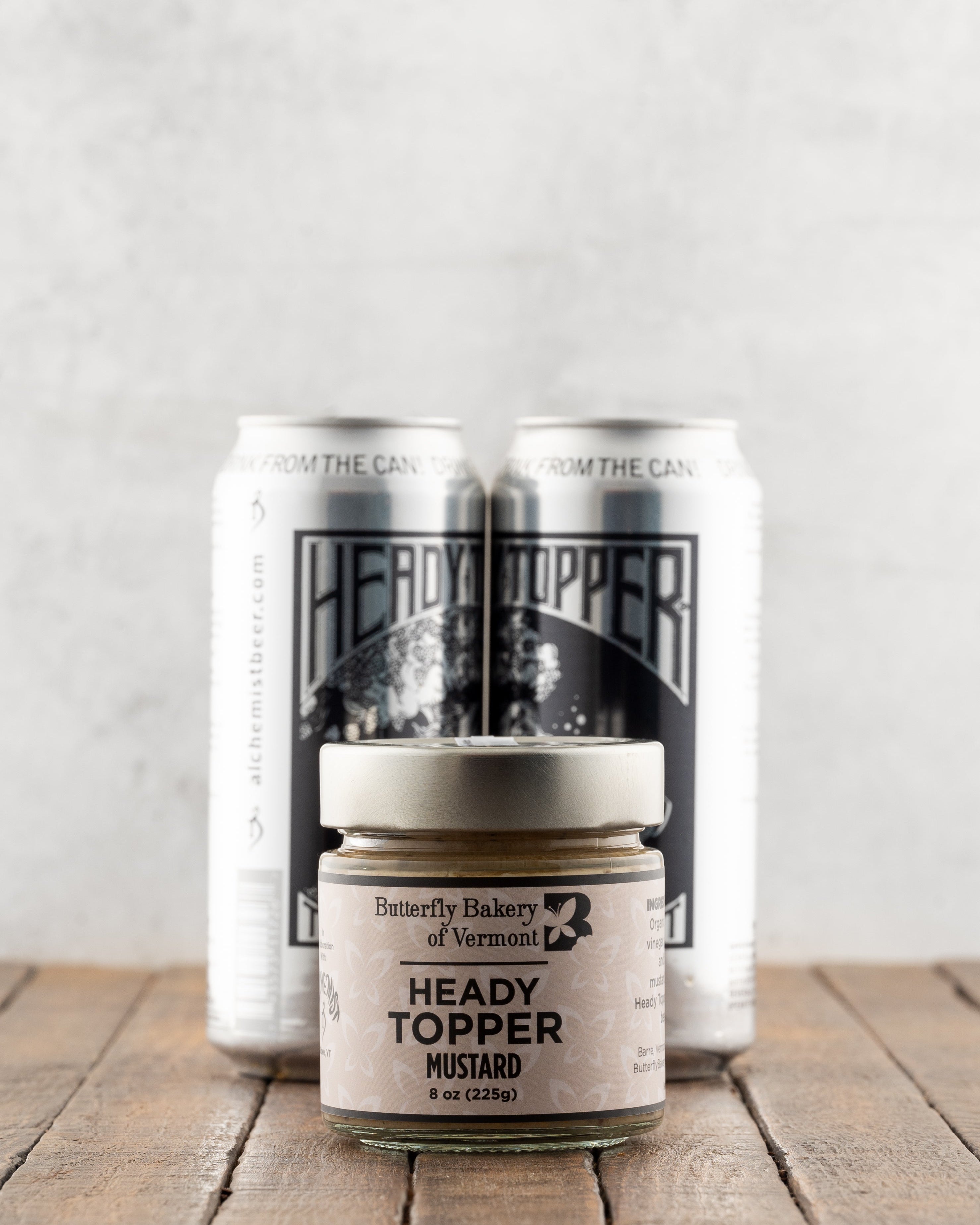 Butterfly Bakery of Vermont Heady Topper Mustard on a wood surface with 2 cans of Heady Topper beer