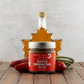 Jar of Maple Sriracha Mustard with a bottle of maple syrup and vegetables on a wooden surface.