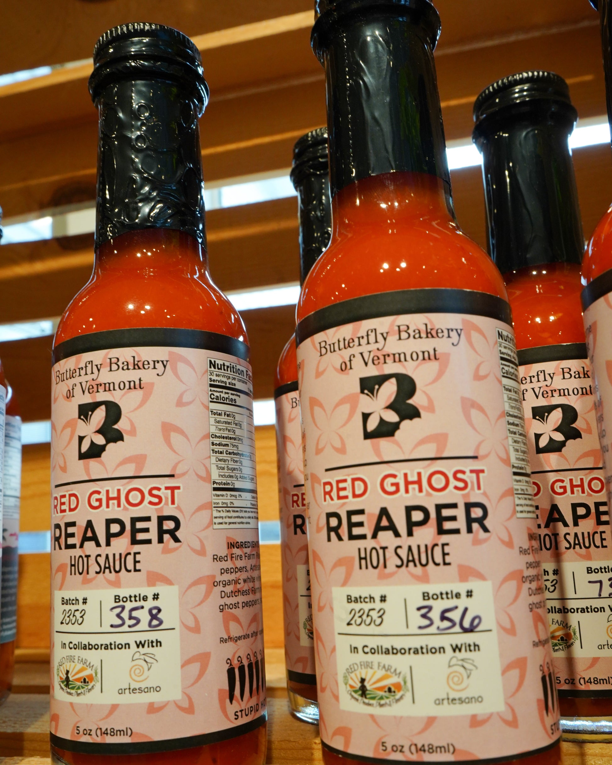 Bottles of Red Ghost Reaper hot sauce on a wooden surface