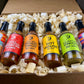 Six bottles of Butterfly Bakery of Vermont hot sauce in a box with decorative wood shavings