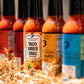 Row of hot sauce bottles with visible labels on a textured surface