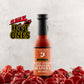 Bottle of Butterfly Bakery of Vermont Smoked Serrano Squash Reaper X Hot Sauce surrounded by red hot peppers on a wooden surface with the 'As Seen On Hot Ones' logo