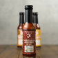 Bottle of Chipotles In Adobo hot sauce from Butterfly Bakery of Vermont on a wooden tabletop