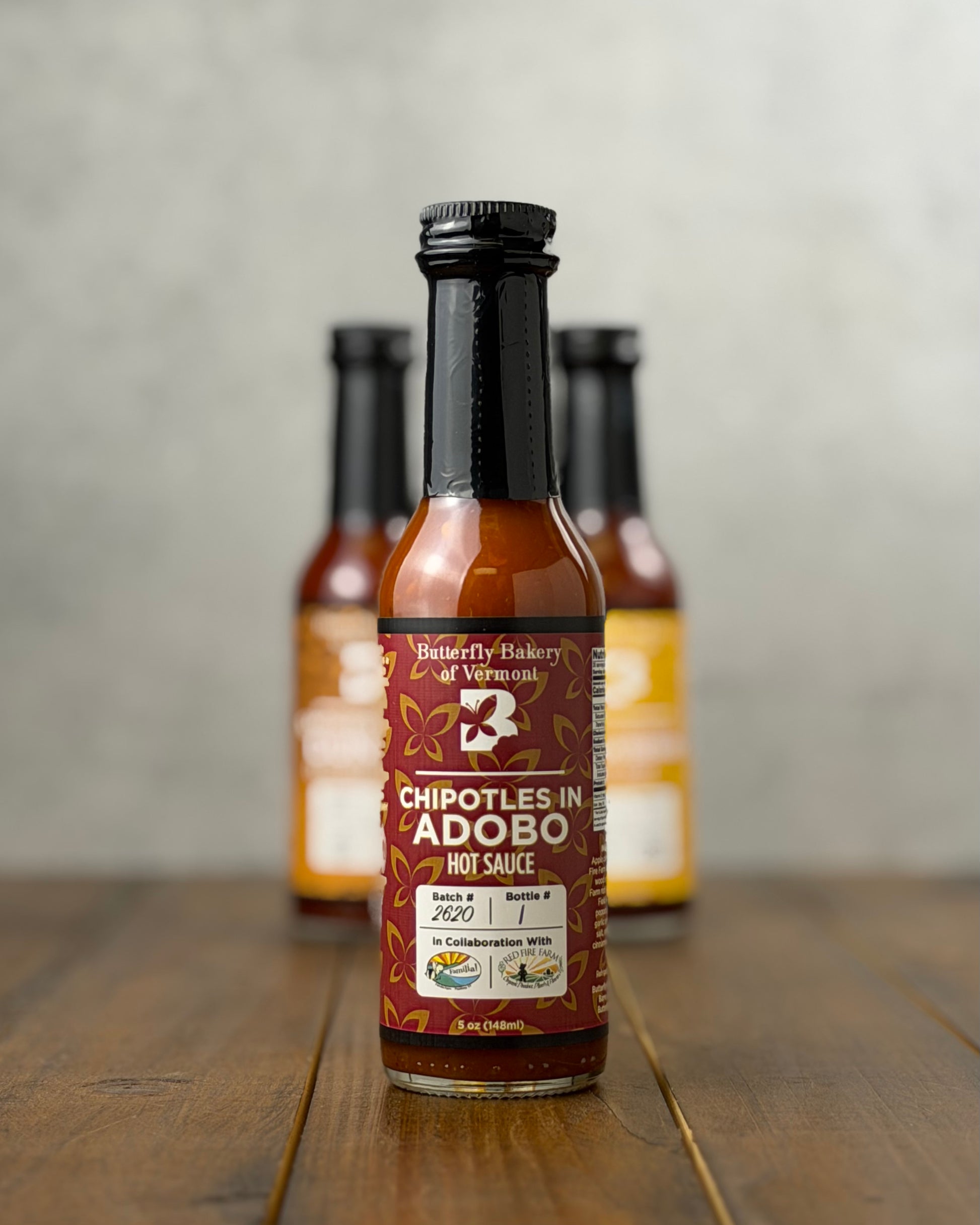 Bottle of Chipotles In Adobo hot sauce from Butterfly Bakery of Vermont on a wooden tabletop