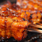 Close-up of skewered grilled satay coated with hot sauce on a grill