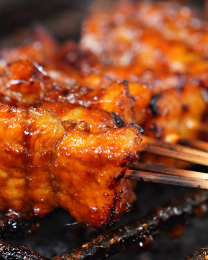 Close-up of skewered grilled satay coated with hot sauce on a grill