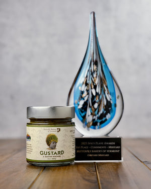 Jar of mustard and an award it won on a wooden surface with a gray background