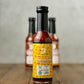 Bottle of Honey Habanero Strawberry hot sauce from Butterfly Bakery of Vermont on a wooden tabletop