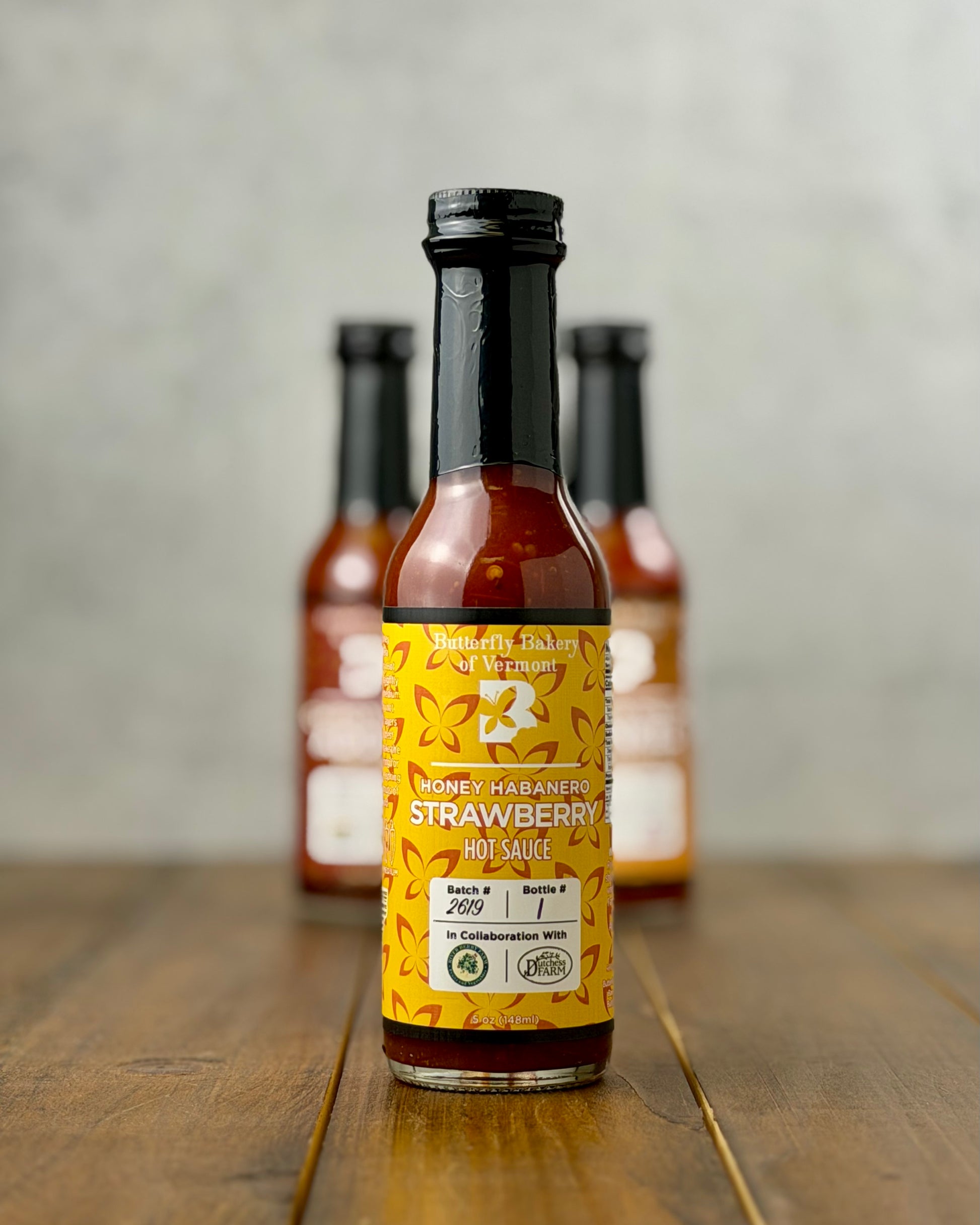 Bottle of Honey Habanero Strawberry hot sauce from Butterfly Bakery of Vermont on a wooden tabletop
