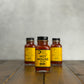 Three 2oz bottles of Hot House hot sauce on a wooden surface with a gray background