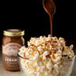 Bowl of popcorn with caramel being drizzled over it, next to a jar of caramel sauce.