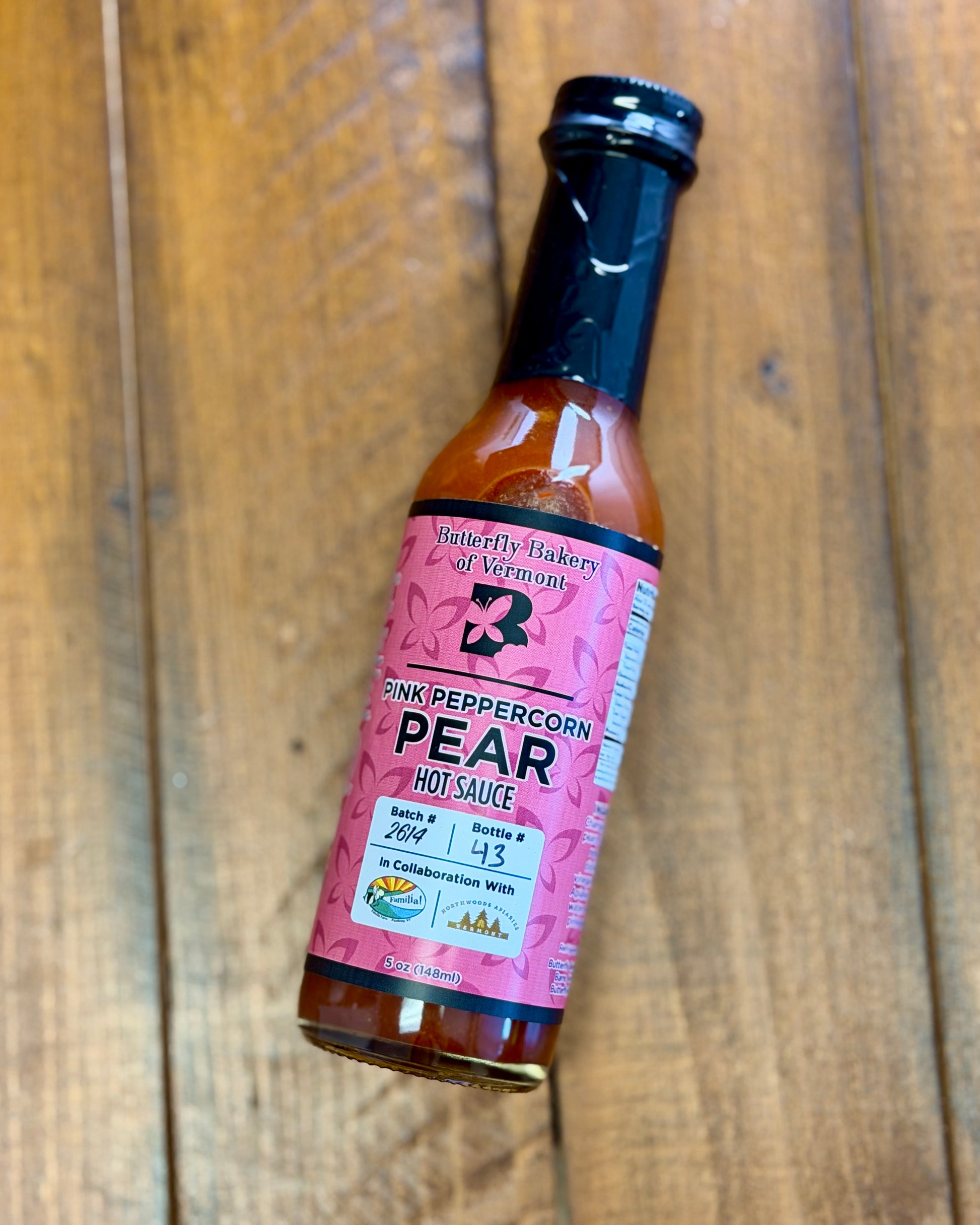 Bottle of Pink Peppercorn Pear hot sauce from Butterfly Bakery of Vermont on a wooden tabletop