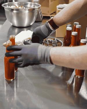 Putting caps on bottles of hot sauce