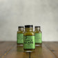 2oz bottle of Garlic Scape Sauce on a wooden surface with a neutral background