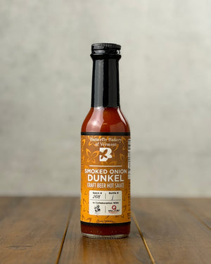 Bottle of Smoked Onion Dunkel Craft Beer hot sauce from Butterfly Bakery of Vermont on a wooden tabletop