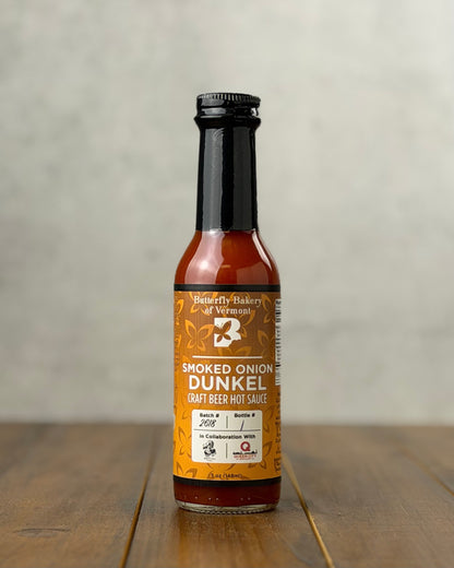 Bottle of Smoked Onion Dunkel Craft Beer hot sauce from Butterfly Bakery of Vermont on a wooden tabletop