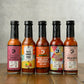 Butterfly Bakery of Vermont's 5 hottest hot sauces lined up on a wood surface and a gray background