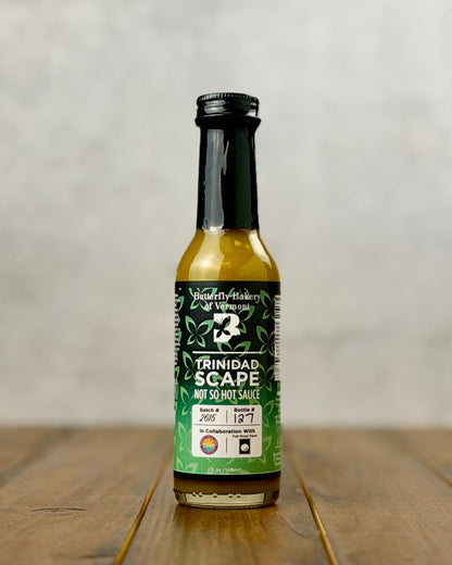 Bottle of Trinidad Garlic Scape sauce from Butterfly Bakery of Vermont on a wooden tabletop