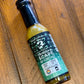 Bottle of Trinidad Garlic Scape sauce from Butterfly Bakery of Vermont on a wooden tabletop