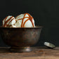 Metal bowl of vanilla ice cream drizzled with Fat Toad Farm caramel