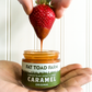 Strawberry being dipped into Fat Toad Farm Original Caramel from Butterfly Bakery of Vermont