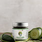 Jar of Gustard Mustard from Butterfly Bakery of Vermont on a wood surface surrounded by garlic scapes, cucumber and jalapeno